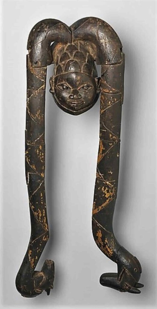  Esta máscara, también es salida del taller de Asamu Fagbite pero sin precisar si fue obra suya o de su hijo Falola Edun. Tal vez por eso se data entre 1930 a 1971. Realizada en Idahin, República de Benin, dentro del grupo yoruba, Ketu. Madera, clavos metálicos, pigmento. Medidas: 104.1 × 48.3 × 27.9 cm. Donada por Roda y Gilbert Graham, 1992. Nº rg: 1992.225.1